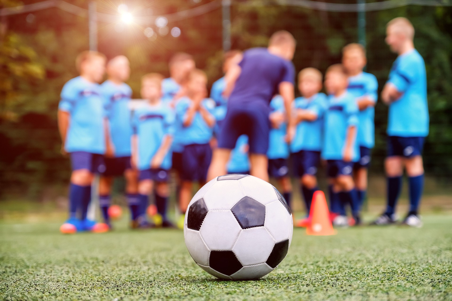 Soccer ball and blurred youth soccer team with coach on the field