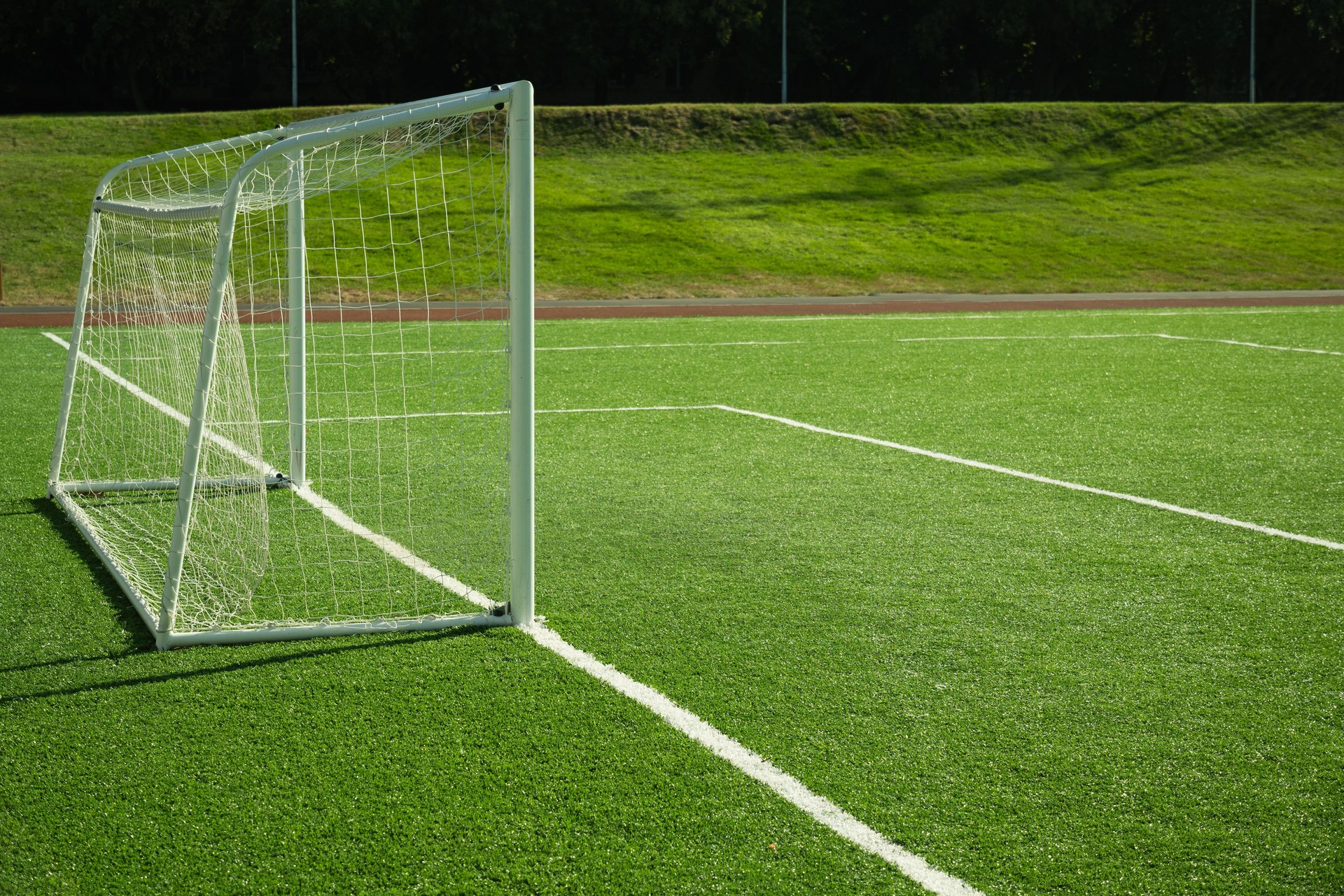 Soccer goal on field with artificial green grass. Outdoors.